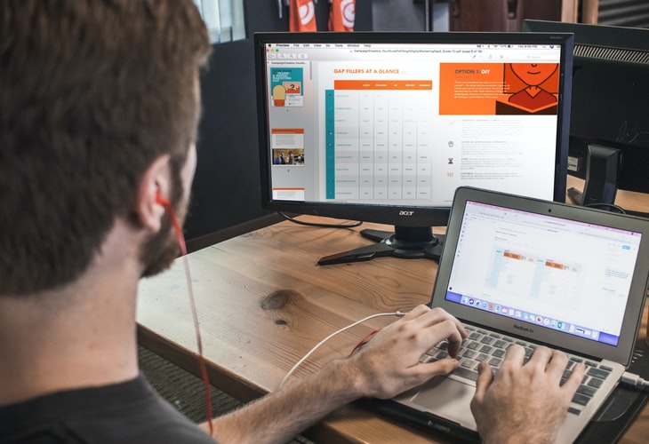 Um homem aplicando uma comunicação integrada de Marketing em seu computador no trabalho.