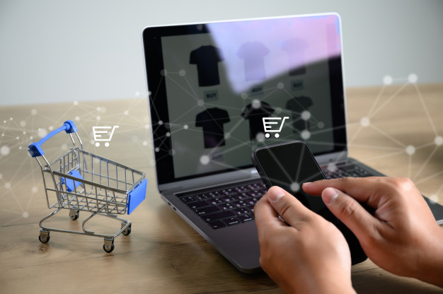 Imagem de um computador aberto em uma loja online, ao lado há um carrinho de compras